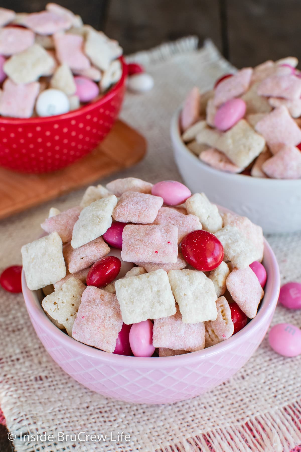 Three bowls filled with a sweet chex mix and M&M candies.