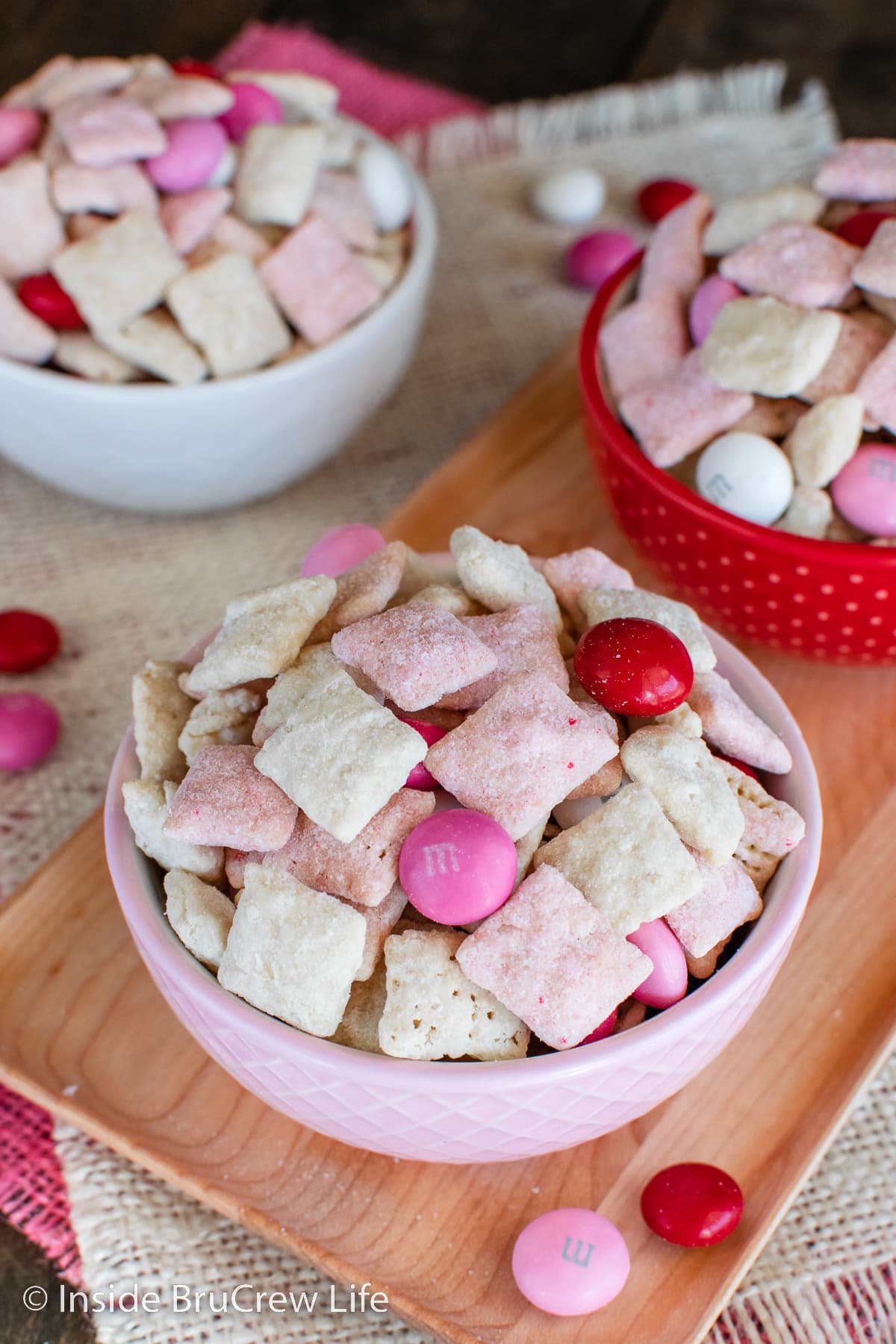 Three bowls of sweet chex snack mix with M&M's.