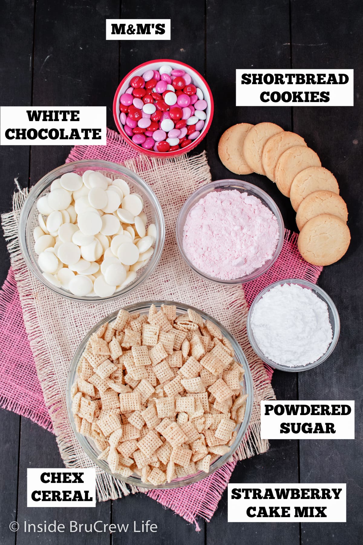 A dark board with bowls of ingredients needed to make muddy buddies.