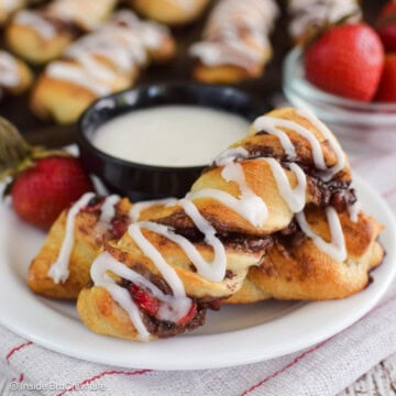 Pastry twists on a white plate with a bowl of frosting.