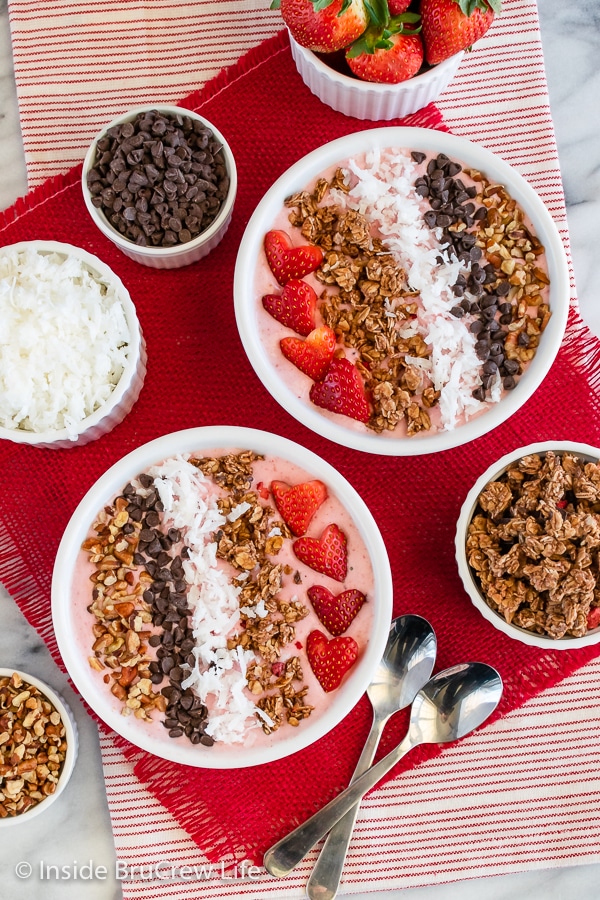 Overhead picture of white bowls filled with strawberry smoothie and toppings.