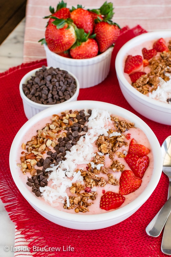 A white bowl filled with a strawberry smoothie and toppings.