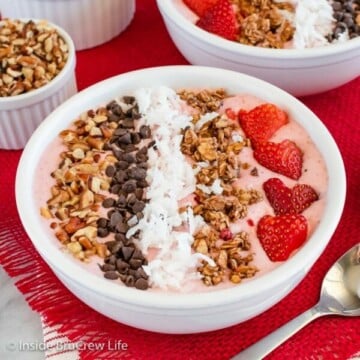 A white bowl with a pink smoothie and toppings in it.