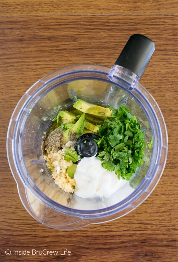 A blender filled with the ingredients needed to make a homemade avocado lime dressing.
