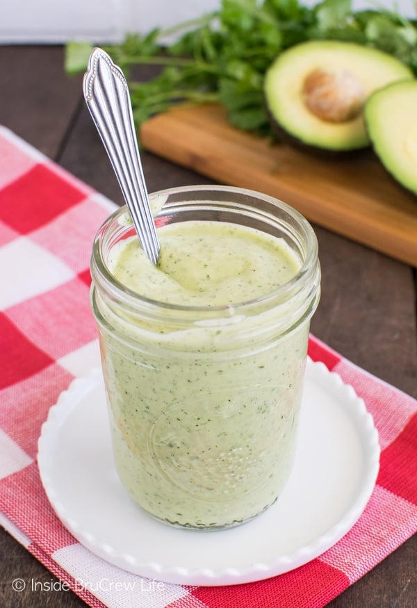 A clear jar filled with avocado salad dressing and a spoon.