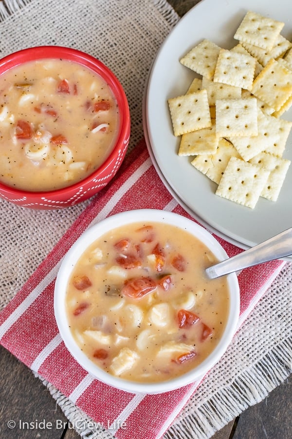 Overhead picture of two red and white bowls filled with cheesy chicken soup and a plate of crackers