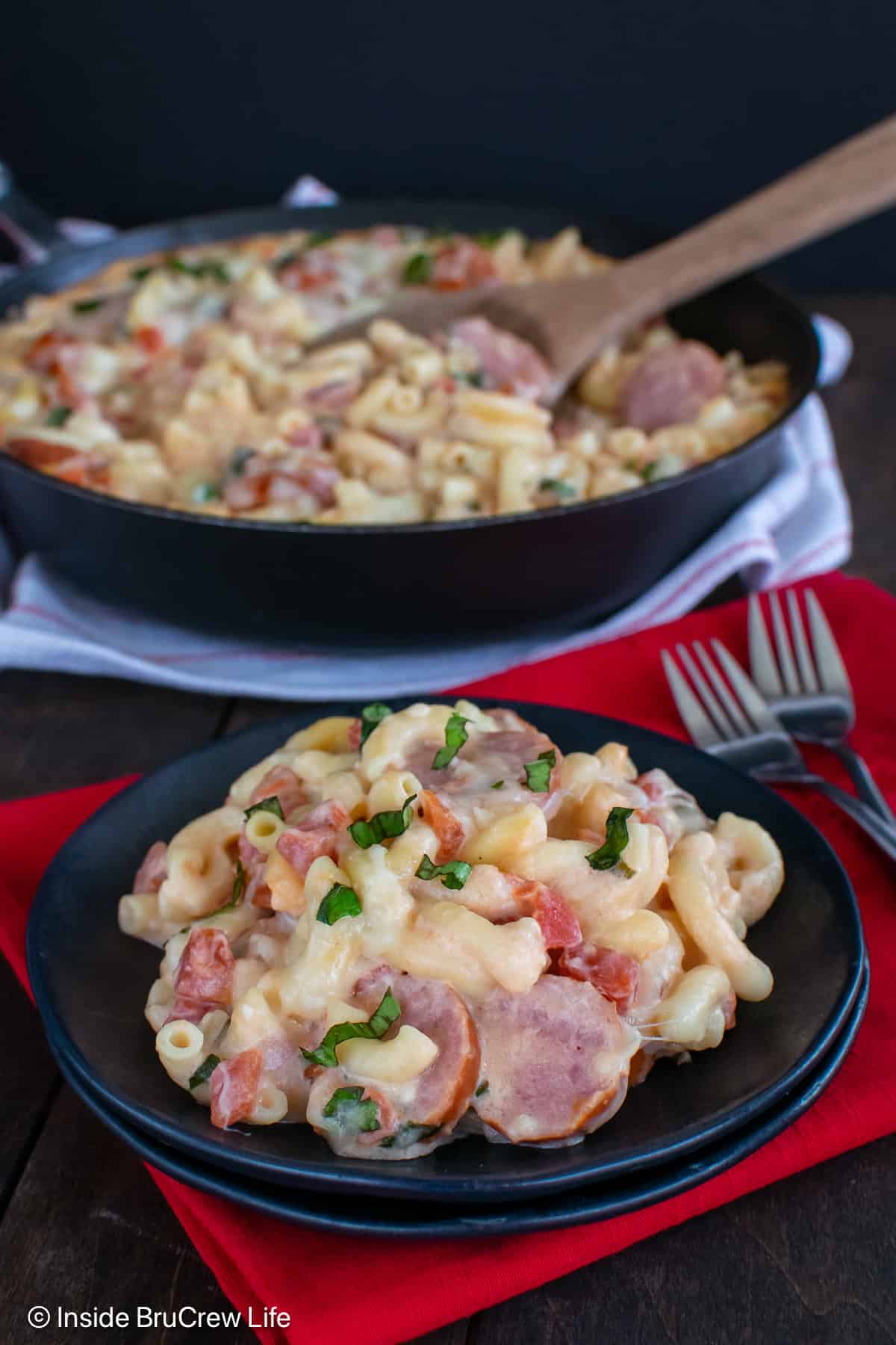 Smoked sausage pasta on a black plate.