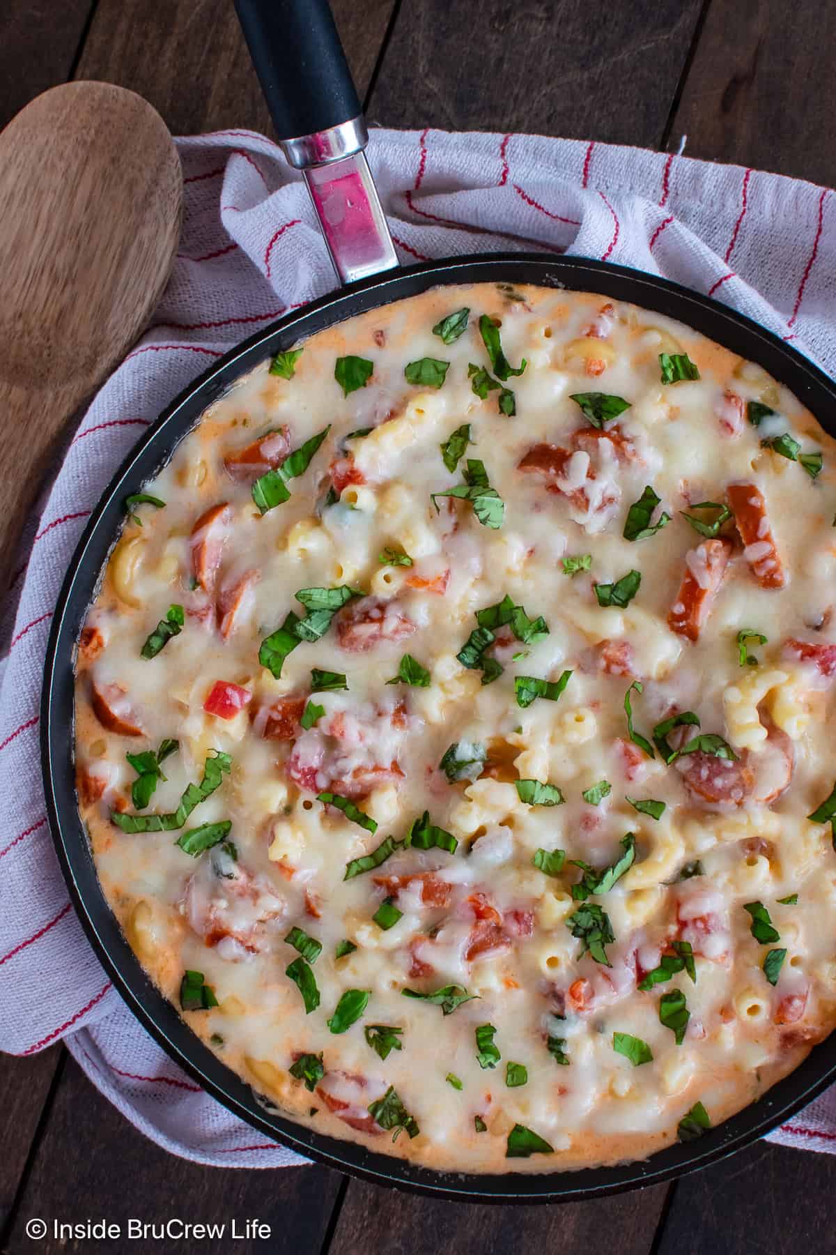 An overhead photo of a skillet filled with cheesy smoked sausage pasta.