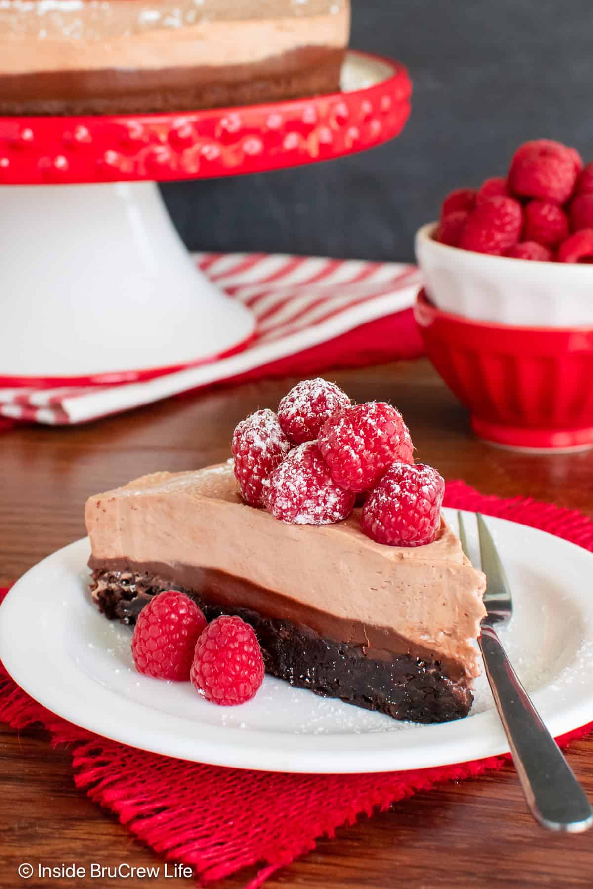 A white plate with a slice of layered Nutella brownie mousse cake.