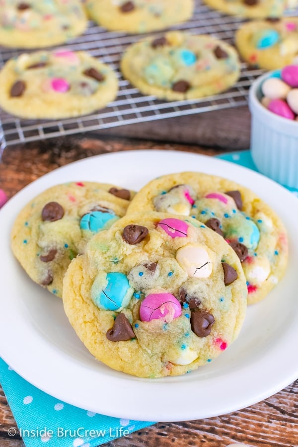 A white plate with three vanilla pudding cookies with candy, sprinkles, and chocolate chips on it