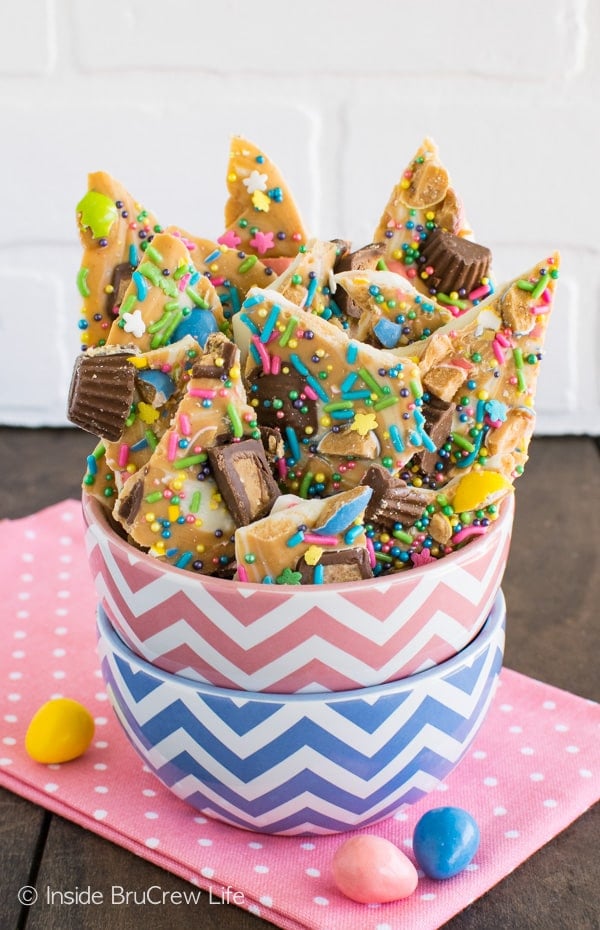 A pink and blue bowl full of peanut butter and chocolate bark loaded with Easter sprinkles.