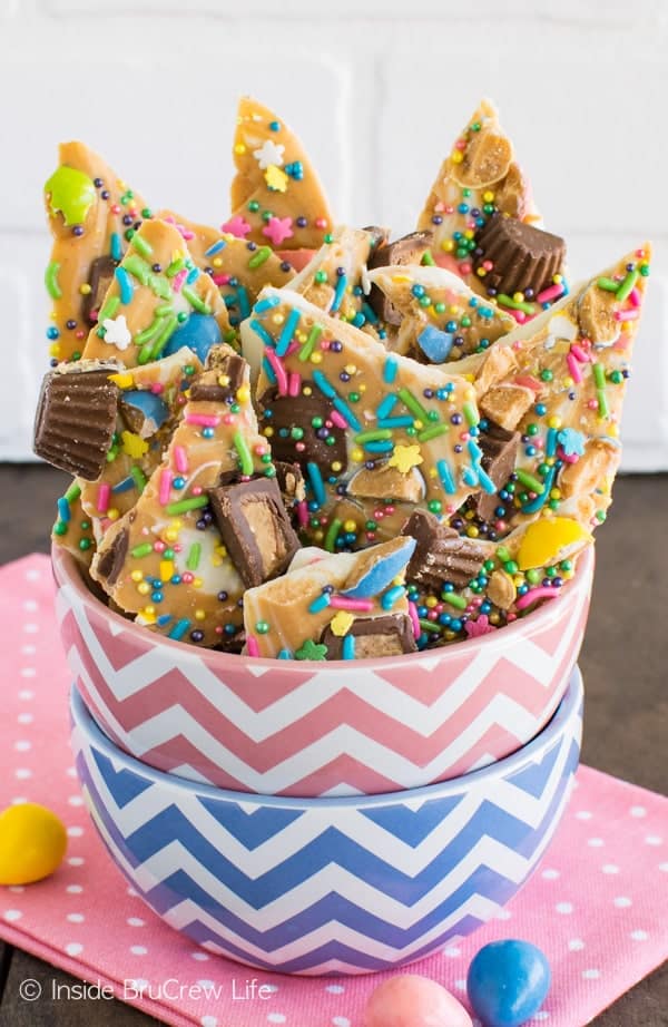 A pink and blue bowl full of peanut butter and chocolate bark loaded with Easter sprinkles.