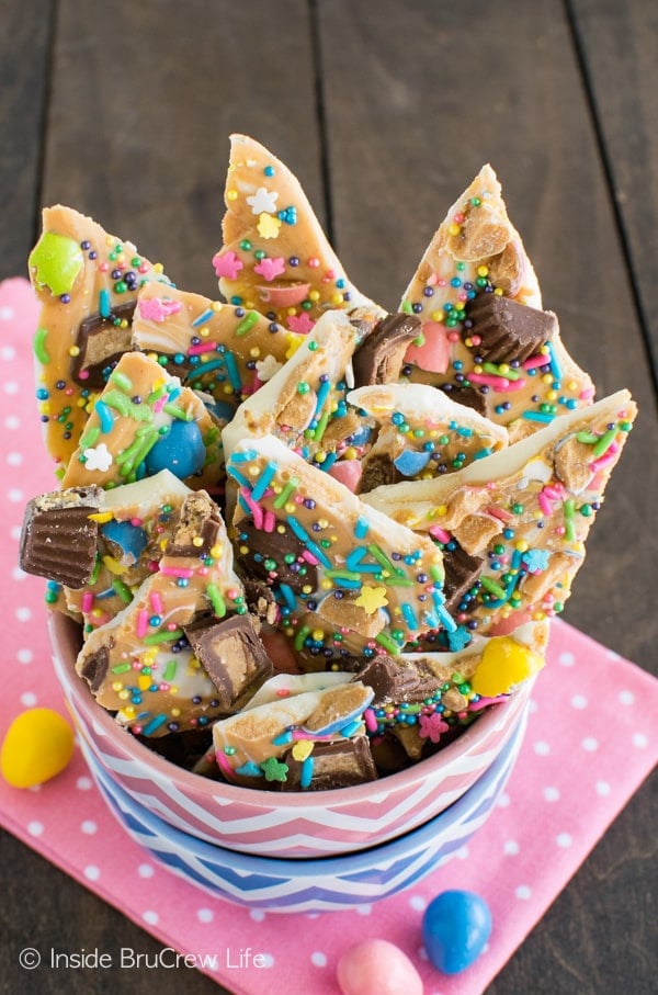 A pink and blue bowl full of peanut butter and chocolate bark loaded with Easter sprinkles.