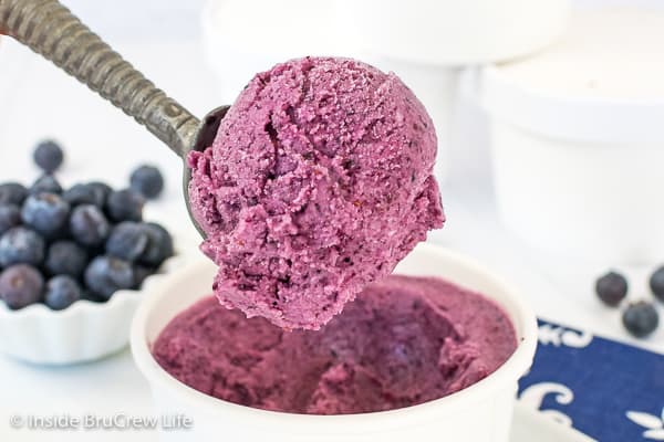 A white bowl with a spoon lifting out a scoop of blueberry banana frozen yogurt