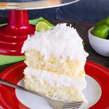 A slice of Key Lime Cake frosted with coconut buttercream in the center and on top