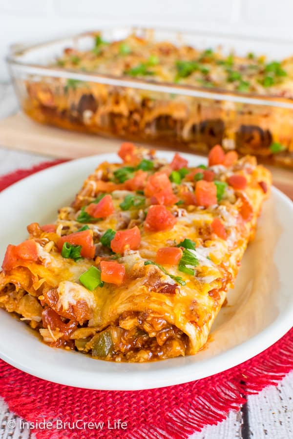 A white plate on a red towel with two Monterey Chicken Enchiladas on it