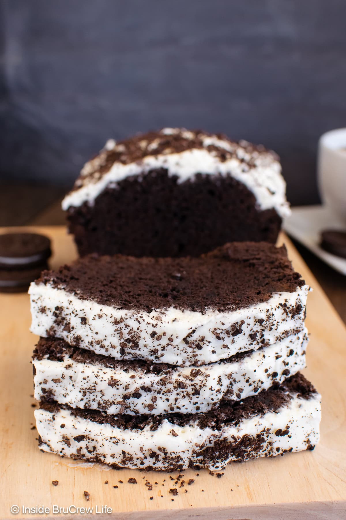 Slices of chocolate banana bread with frosting on a cutting board.