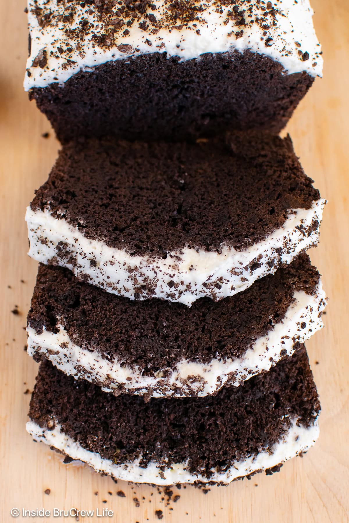 Slices of chocolate banana bread with Oreo frosting on a cutting board.