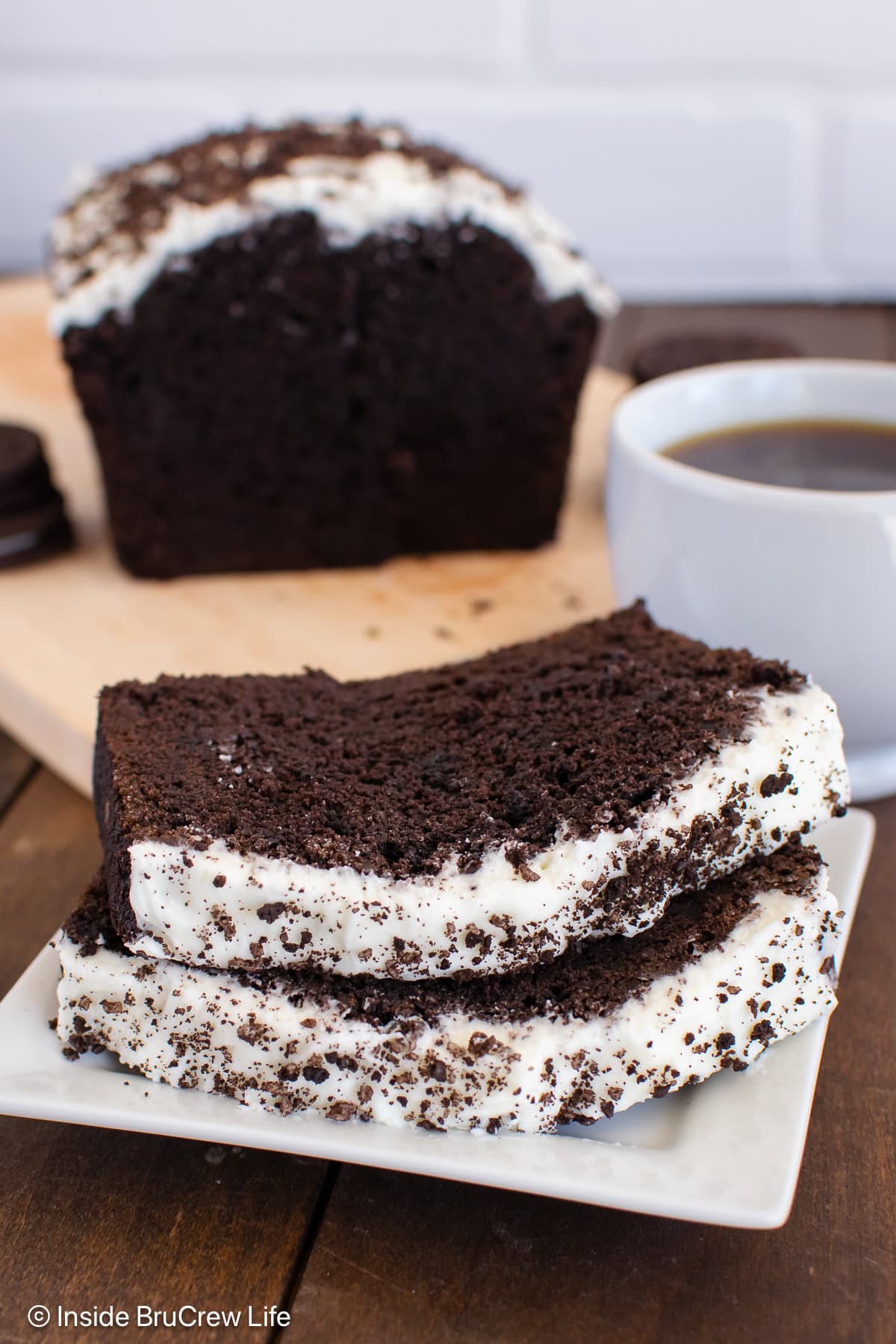 A white plate with two slices of chocolate banana bread on it.