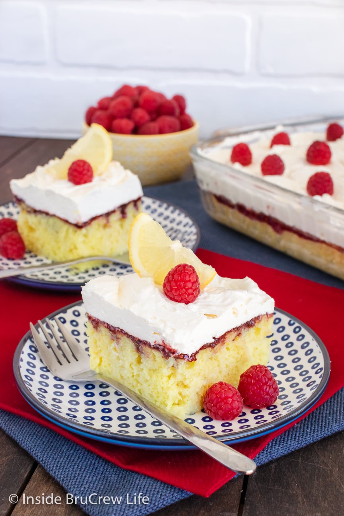 Two plates with frosted lemon cake squares on it.