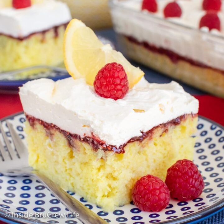 Lemon cake squares with raspberry and lemon topping on blue plates.