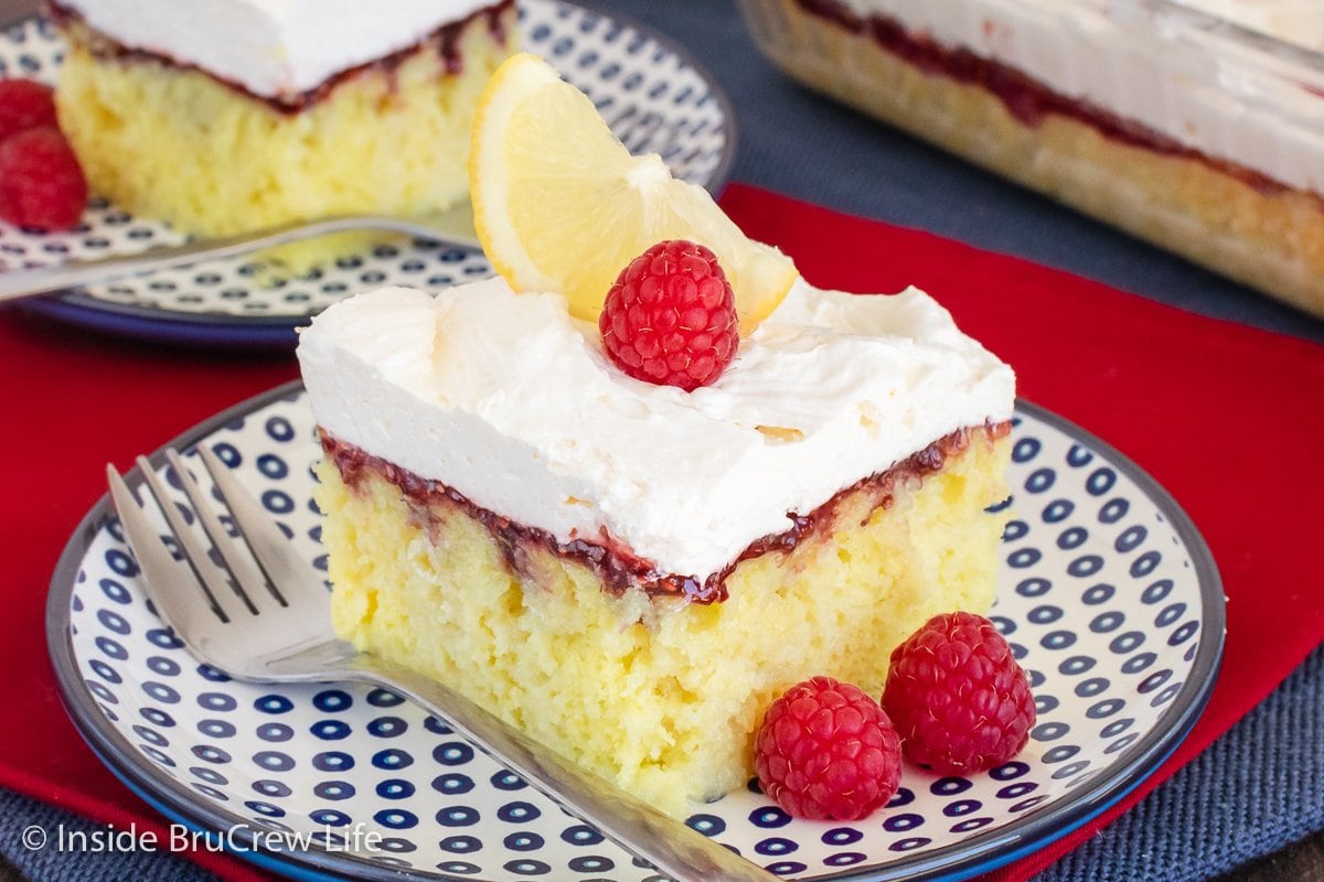 Lemon cake squares with raspberry and lemon topping on blue plates.