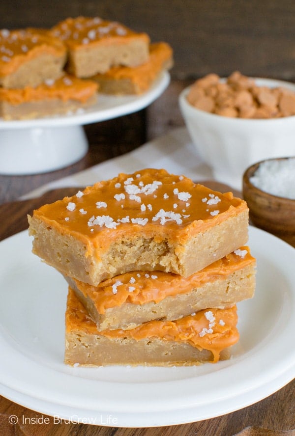 Three salted butterscotch bars on a white plate with a bite out of the top bar