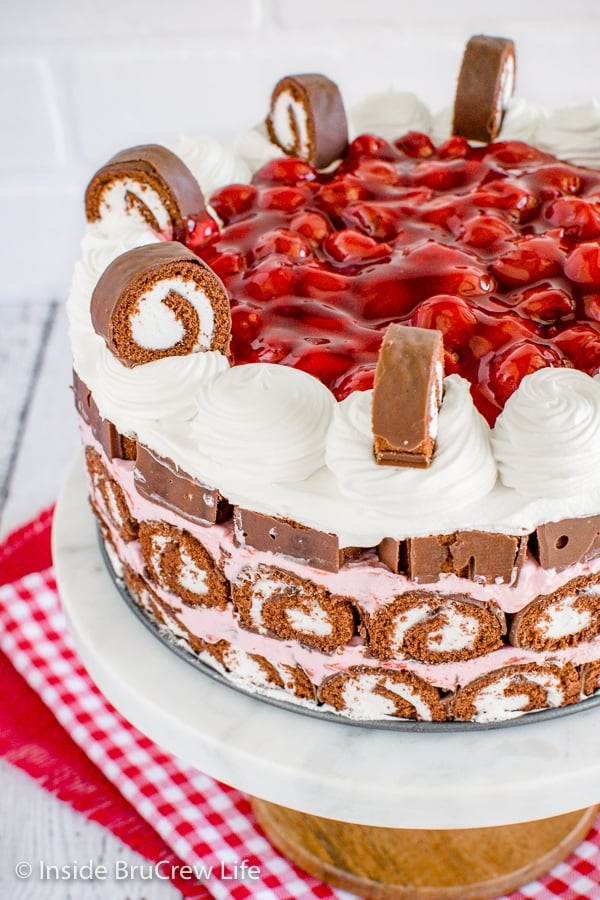 A close up of a no bake cherry swiss rolls cake on a cake plate topped with cherry pie filling
