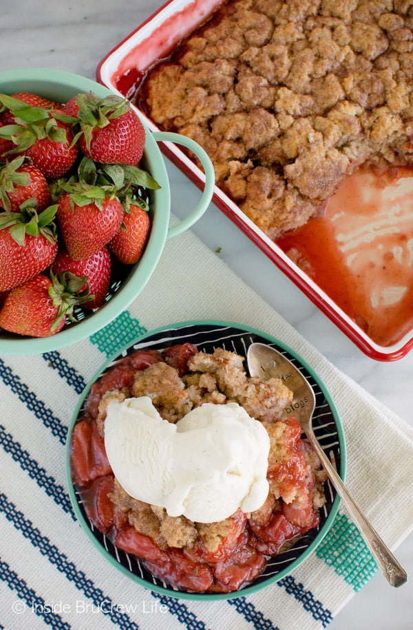 Overhead picture of a plate with strawberry cobbler and vanilla ice cream on it and the pan of cobbler beside it