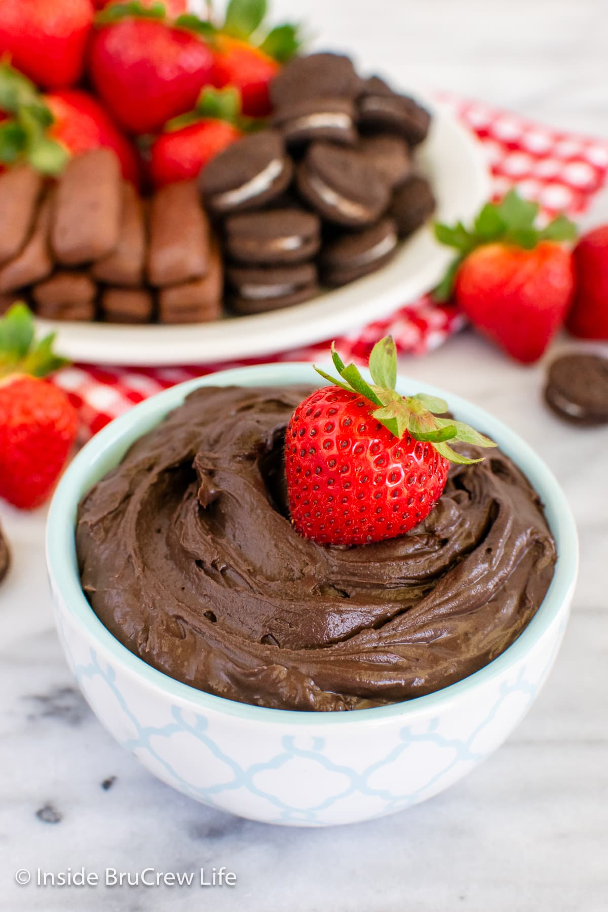 A creamy chocolate cheesecake dip with a strawberry in it.
