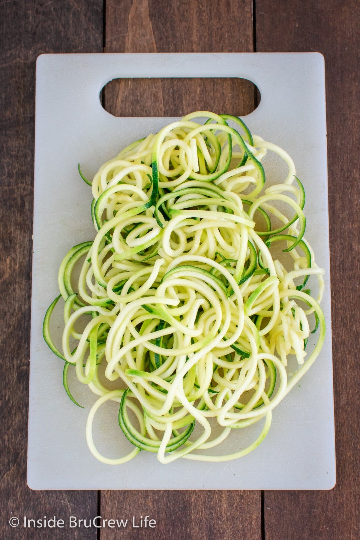 Zucchini noodles on a white cutting board.
