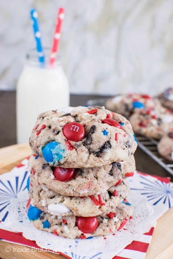 A stack of four Fireworks Cookies and Cream Cookies on a white doily with a glass of milk behind it
