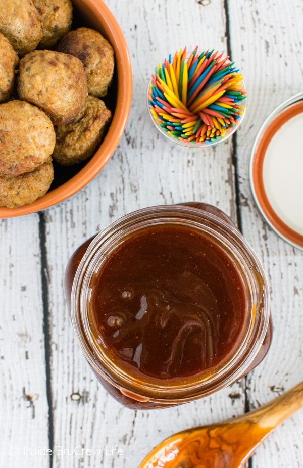 An overhead picture of a jar of honey sriracha barbecue sauce and a bowl of baked meatballs