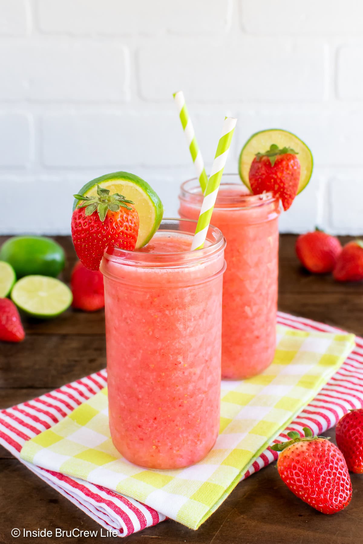 Two glass cups filled with a strawberry drink and straws.