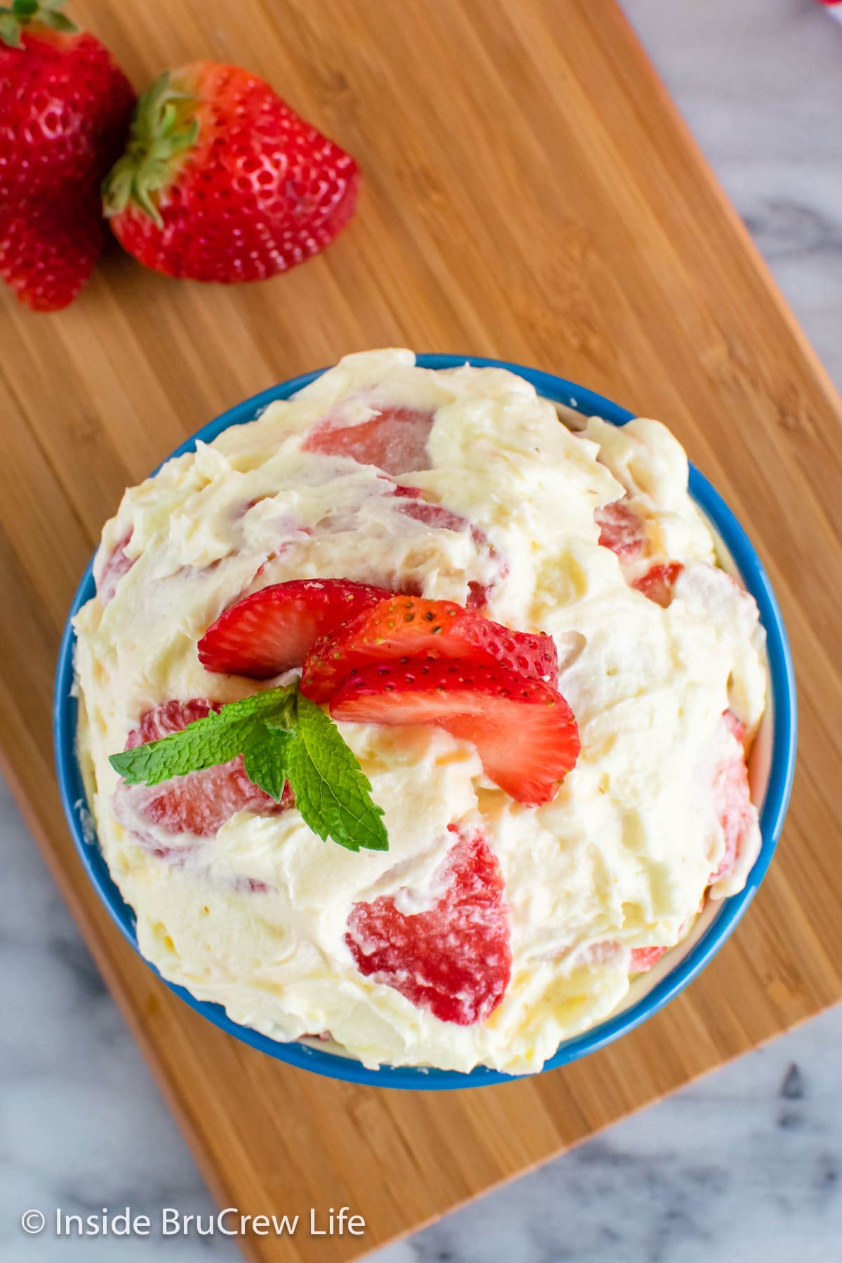 Overhead picture of a blue bowl filled with a fluff salad loaded with strawberries.