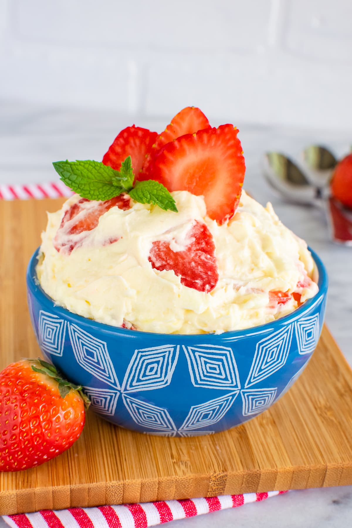 A blue bowl filled with lemon fluff and sliced strawberries.