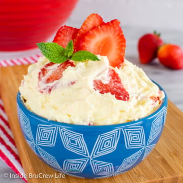 A blue bowl filled with lemon fluff and sliced strawberries.