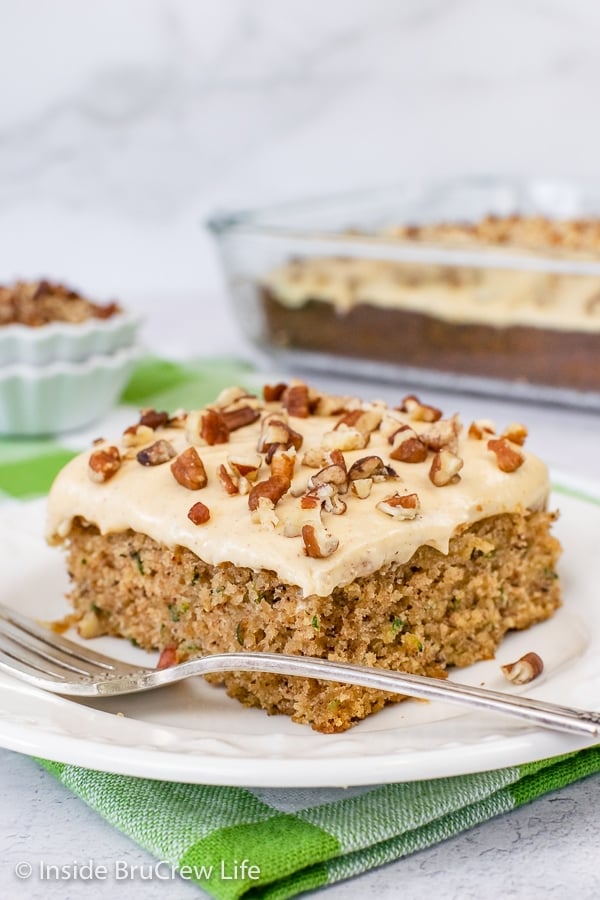 A slice of cake topped with caramel frosting and chopped pecans.