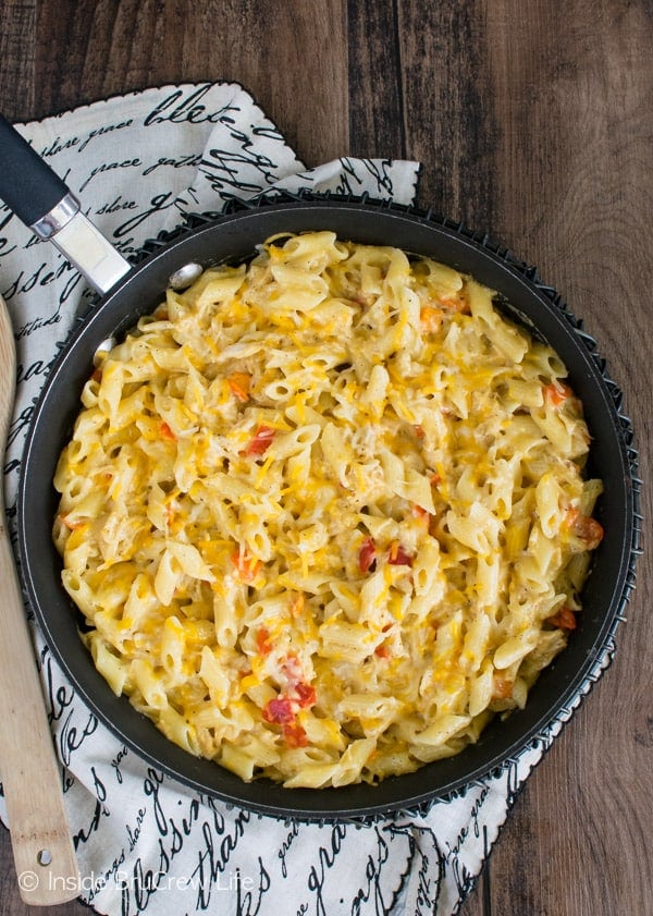 Overhead picture of a towel with a black skillet filled with cheesy chicken pasta on it.