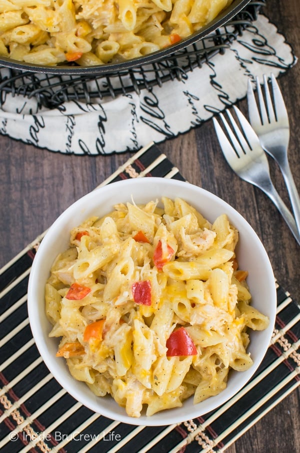 Overhead picture of a white bowl on a black placemat filled with cheesy chicken pasta.