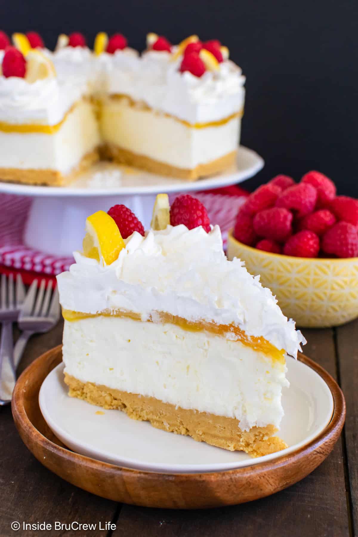 A slice of no bake lemon coconut cheesecake on a plate with the rest behind it.