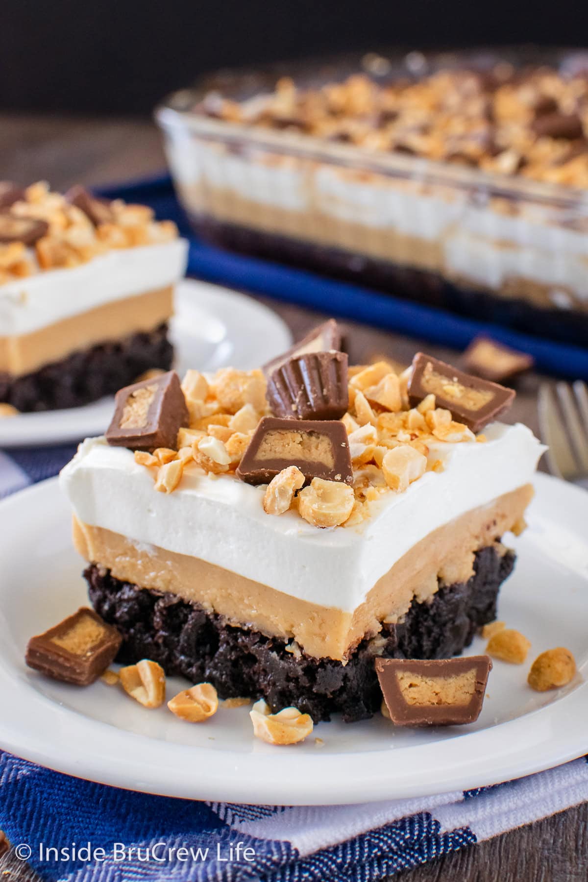A layered brownie dessert with peanut butter on a white plate.