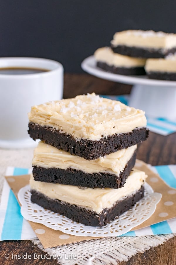 A white doily with three chocolate sugar cookie bars frosted with salted caramel frosting stacked on it