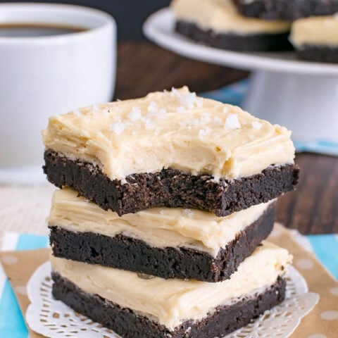 Three chocolate sugar cookie bars frosted with salted caramel frosting stacked on top of each other