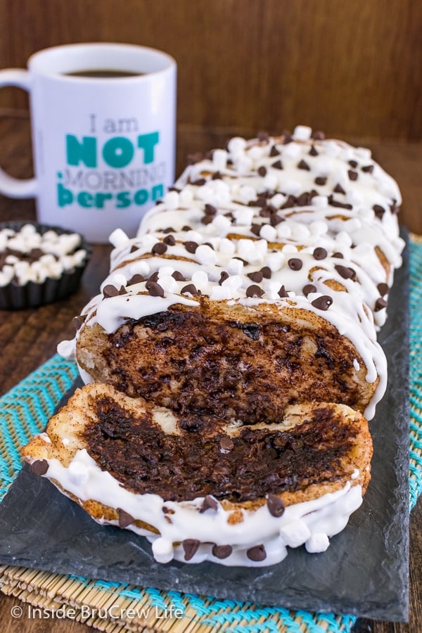 A loaf of gooey s'mores pull apart bread drizzled with marshmallow glaze with one slice lying down