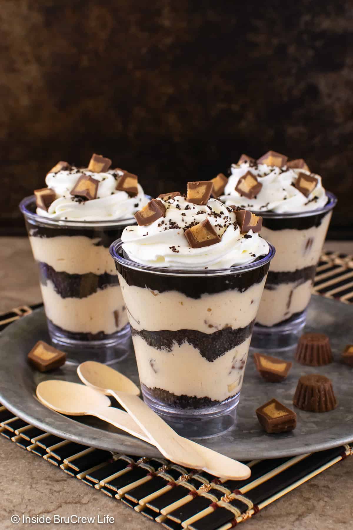 Three peanut butter chocolate mousse parfaits on a silver tray.