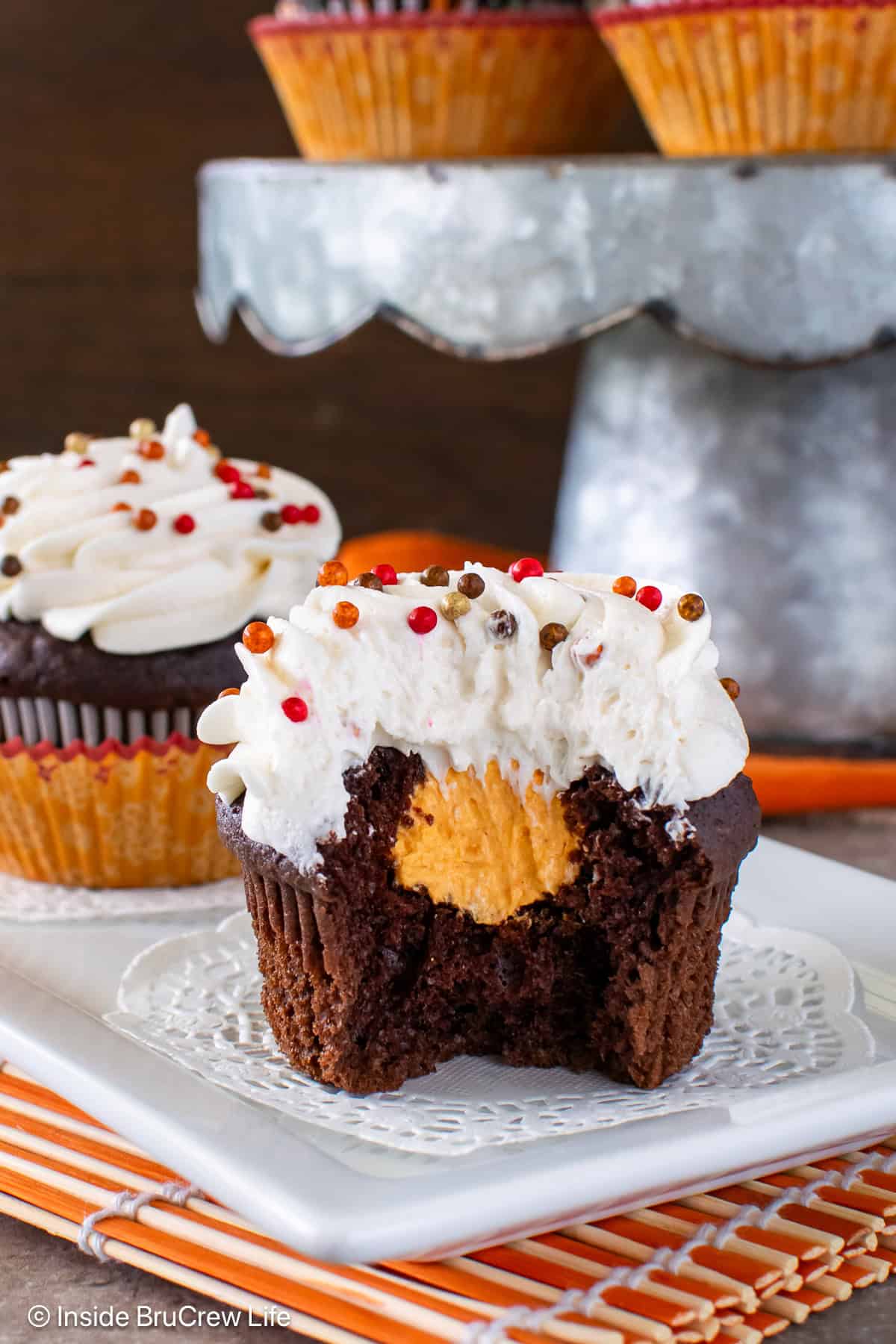 A bite out of a vanilla frosted chocolate cupcake showing the orange cream filling center.