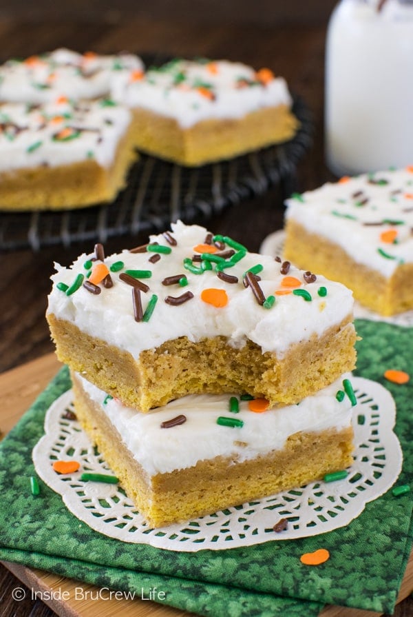 A stack of two frosted pumpkin spice sugar cookie bars stacked on a white doily