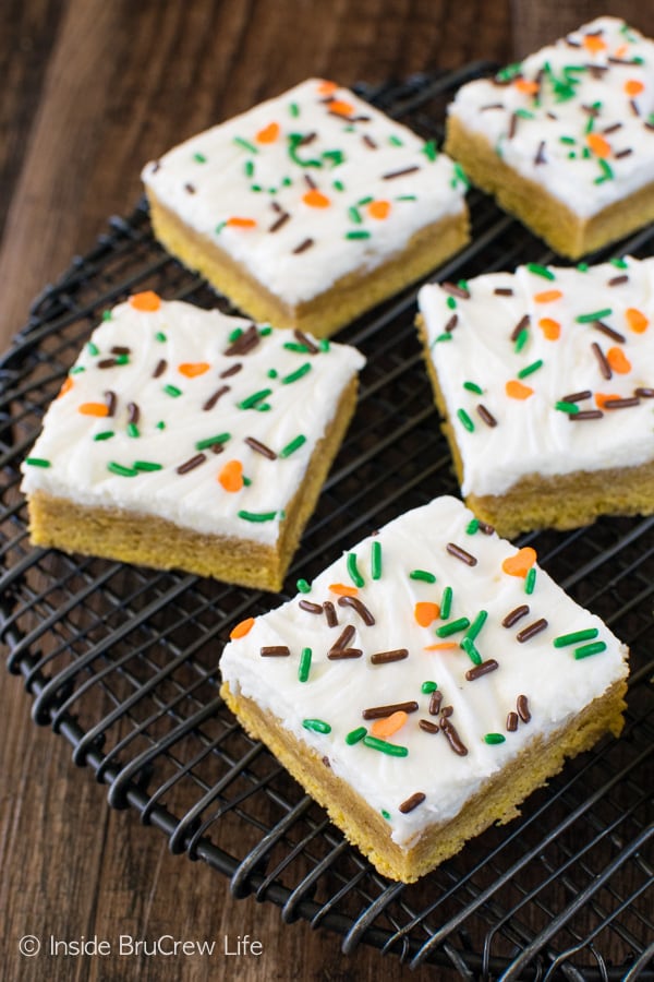 Overhead picture of a black wire rack with frosted pumpkin spice sugar cookie bars with sprinkles on it