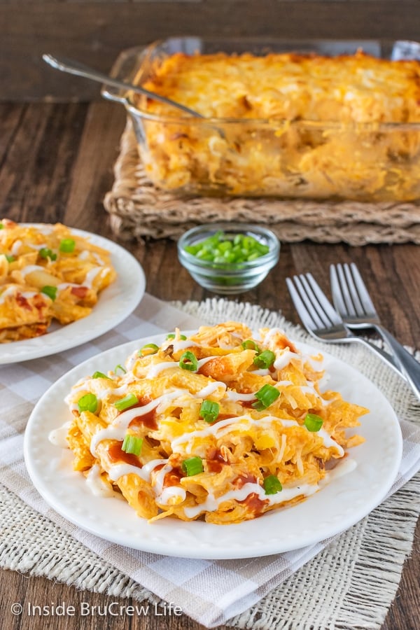 A white plate with buffalo chicken pasta on it and a casserole dish of pasta behind it.